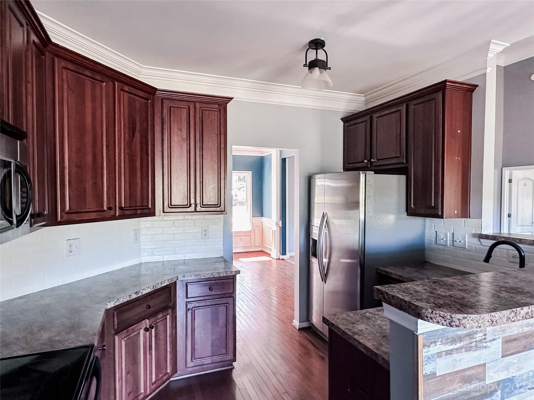181 Weathers Creek Road Troutman, NC 28166 - Photo 6 of 25 a kitchen with granite countertop stainless steel appliances wooden cabinets a refrigerator and a sink