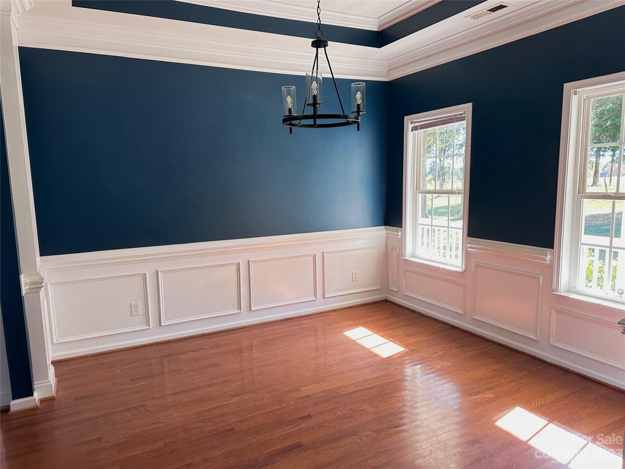 181 Weathers Creek Road Troutman, NC 28166 - Photo 8 of 25 an empty room with wooden floor windows and chandelier