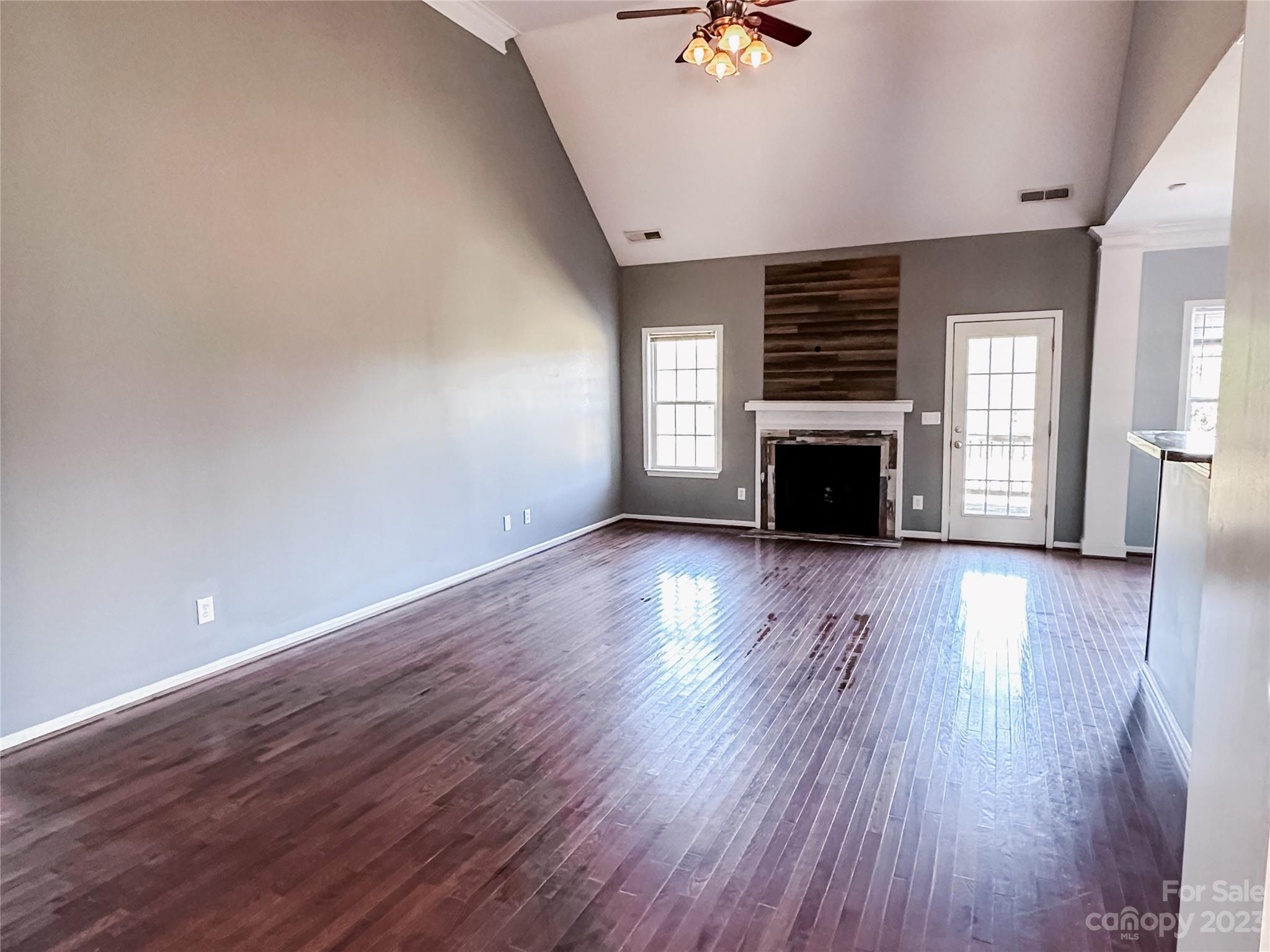 181 Weathers Creek Road Troutman, NC 28166 - Photo 10 of 25 an empty room with wooden floor fireplace and windows