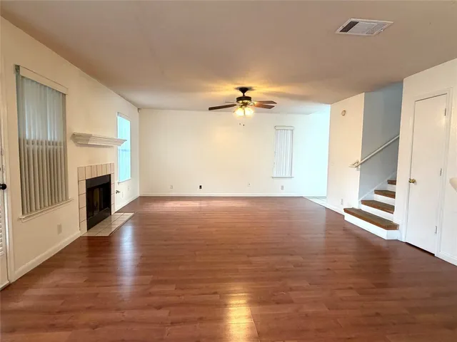 a view of an empty room with wooden floor fireplace and a window