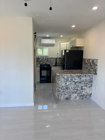 a living room with stainless steel appliances kitchen island granite countertop a couch and a fireplace