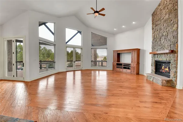 a view of a livingroom with wooden floor a fireplace window a kitchen and chandelier