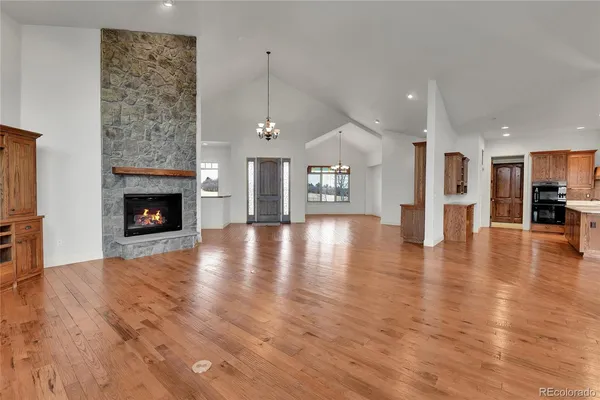 an empty room with wooden floor fireplace and windows