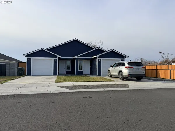 a front view of a house with a garden and parking space