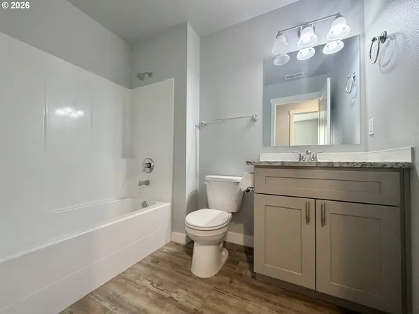 a bathroom with a granite countertop toilet a sink and a mirror