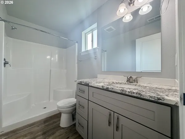 a bathroom with a granite countertop sink a toilet and shower