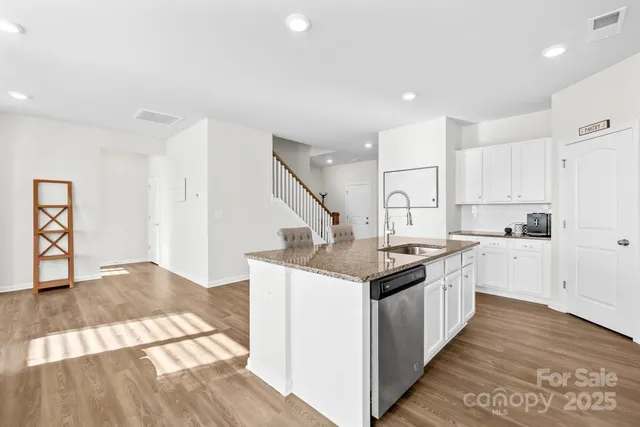 a kitchen with granite countertop a sink and cabinets with wooden floor