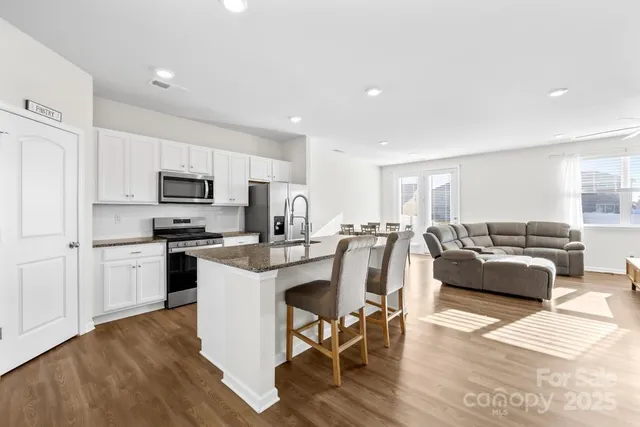 a living room with furniture a kitchen and a stove top oven