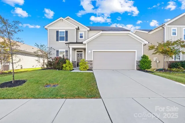 a view of a house with a big yard plants and large tree