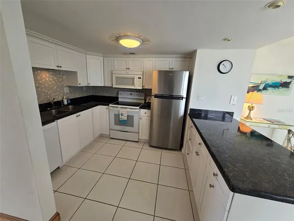 a kitchen with stainless steel appliances granite countertop a refrigerator a sink and white cabinets