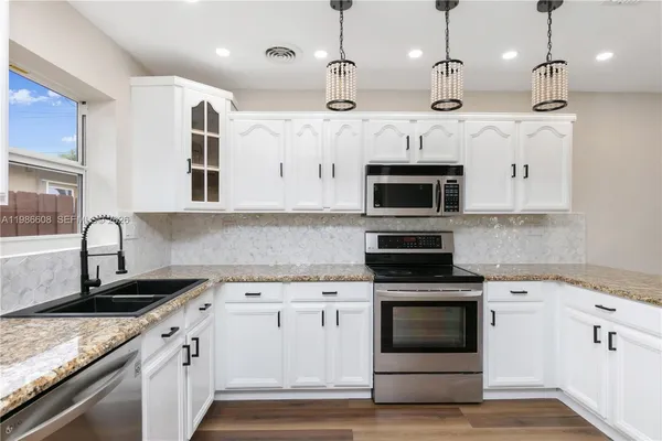 a kitchen with stainless steel appliances granite countertop a stove a sink and a microwave
