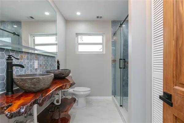 a bathroom with a granite countertop toilet a sink and a mirror