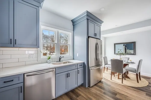 a kitchen with a refrigerator a sink and dishwasher with wooden floor