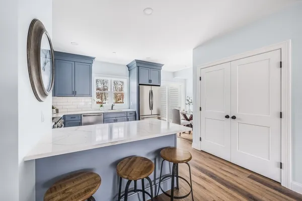 a large white kitchen with stainless steel appliances a counter space and wooden floor