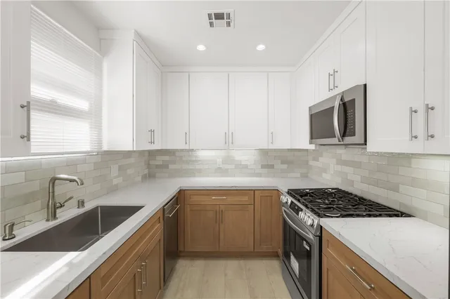 a kitchen with granite countertop cabinets stainless steel appliances a sink and a window