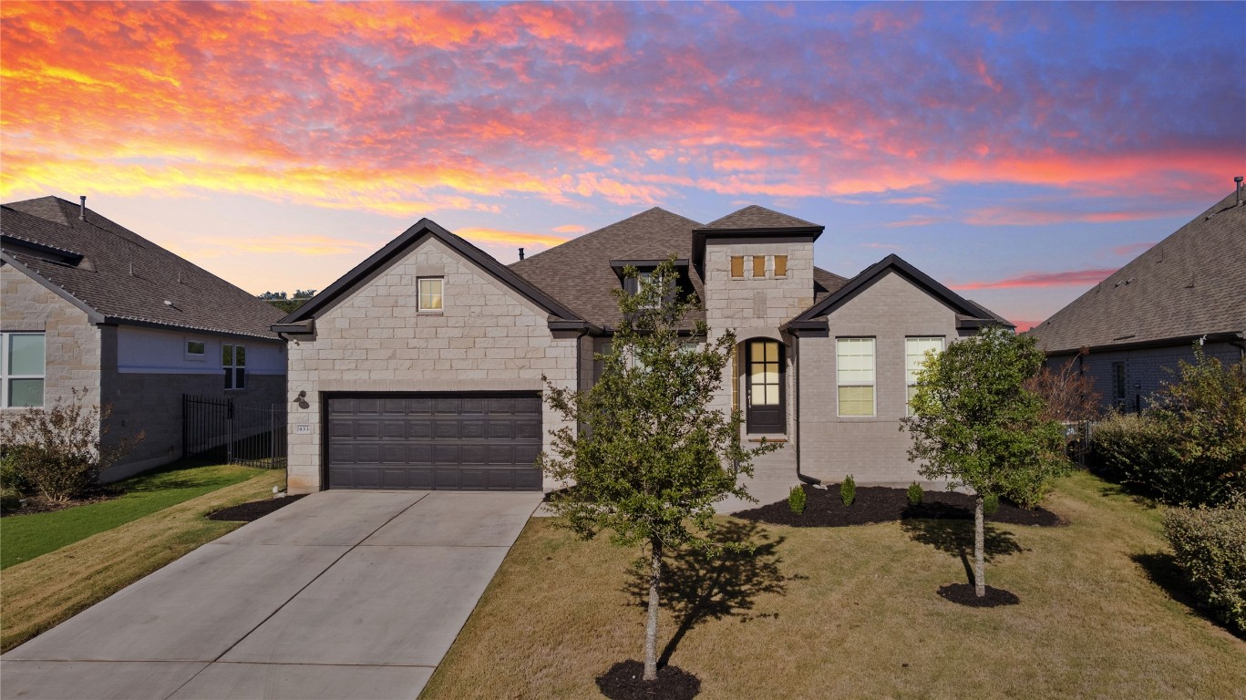 French country home with concrete driveway, stone siding, and a front yard