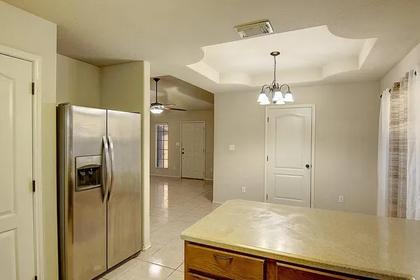 a view of a refrigerator in kitchen and an empty room