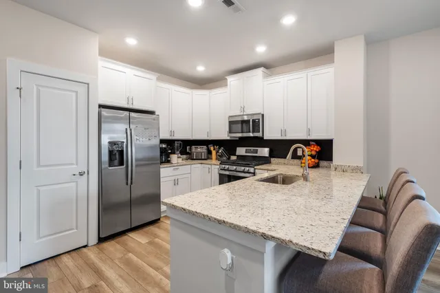 a kitchen with stainless steel appliances granite countertop a refrigerator a sink a stove a microwave and island