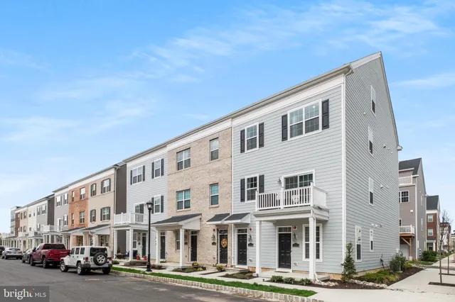 a front view of a building with lot of cars and trees