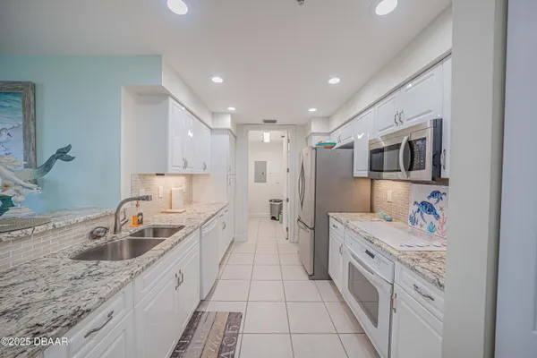 a large white kitchen with stainless steel appliances granite countertop a sink and dishwasher a oven with white cabinets