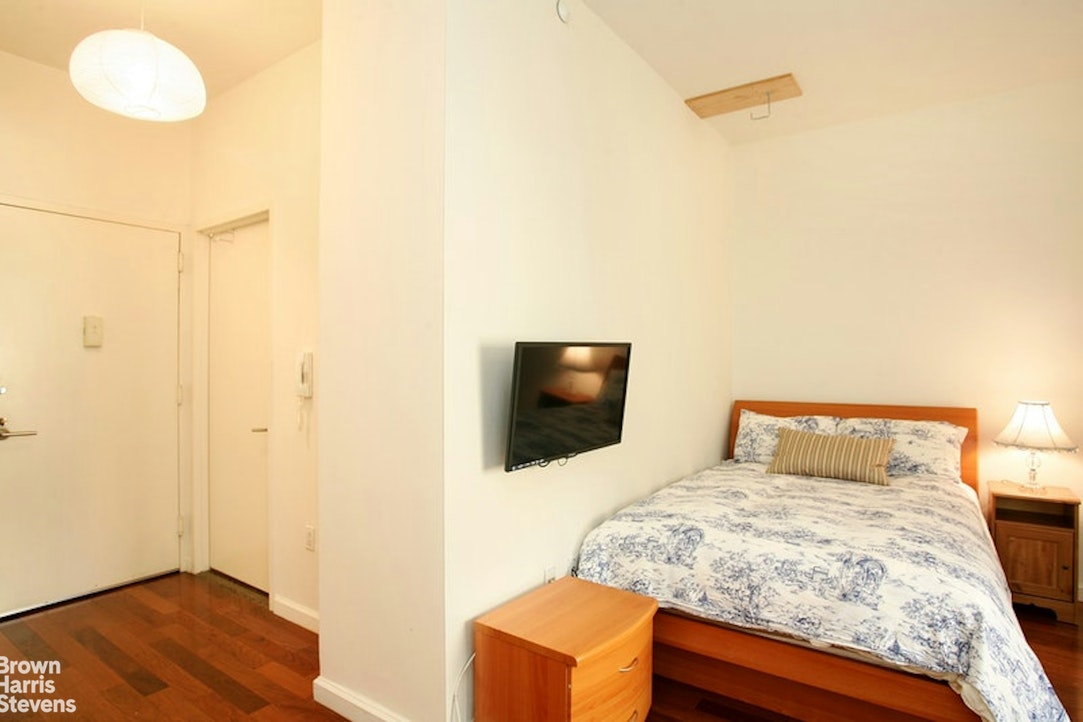 1 Wall Street Court, Unit 1106 Manhattan, NY 10005 - Photo 2 of 4 a bedroom with a bed and flat screen tv