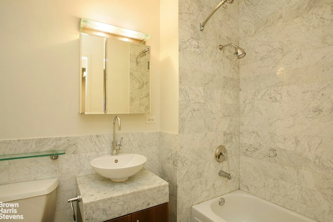 1 Wall Street Court, Unit 1106 Manhattan, NY 10005 - Photo 3 of 4 a bathroom with a sink a toilet and shower