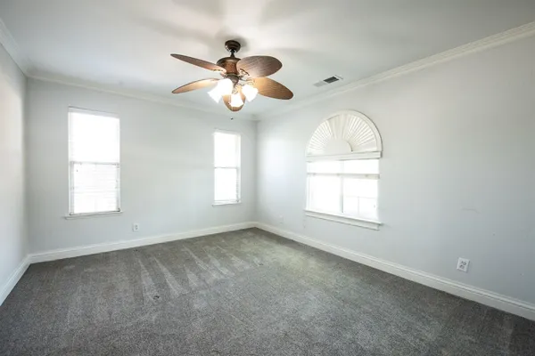 an empty room with windows and chandelier fan