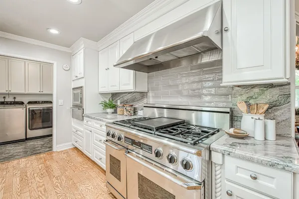 a white kitchen with granite countertop stainless steel appliances