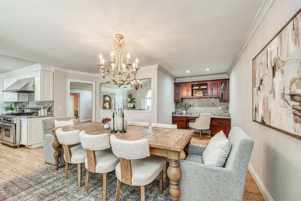a dining room with wooden floor a chandelier a glass table and chairs