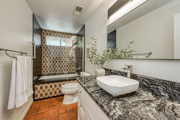 a bathroom with a granite countertop sink toilet a mirror and shower