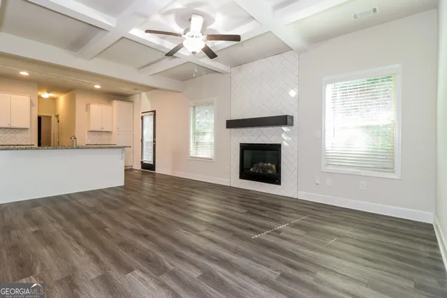 an empty room with wooden floor fireplace and windows