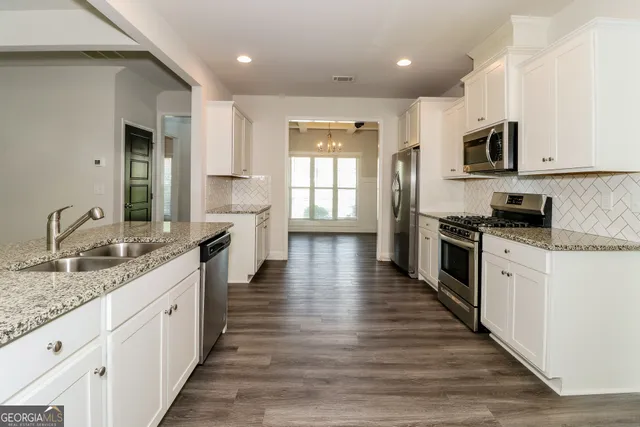 a large kitchen with stainless steel appliances granite countertop a lot of counter space and wooden floors