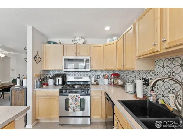 a kitchen with stainless steel appliances a sink a stove a microwave a sink a refrigerator and cabinets