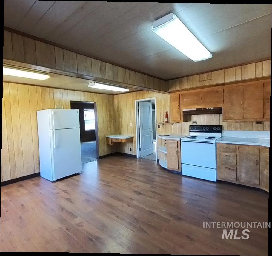418 13th Street Clarkston, WA 99403 - Photo 14 of 26 Kitchen with light countertops, white appliances, dark wood-style floors, wood walls, and under cabinet range hood