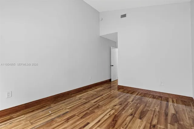 a view of an empty room with wooden floor