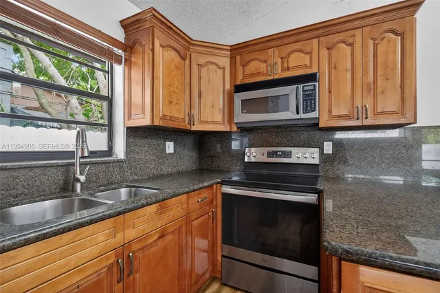 a kitchen with granite countertop a sink a stove and cabinets
