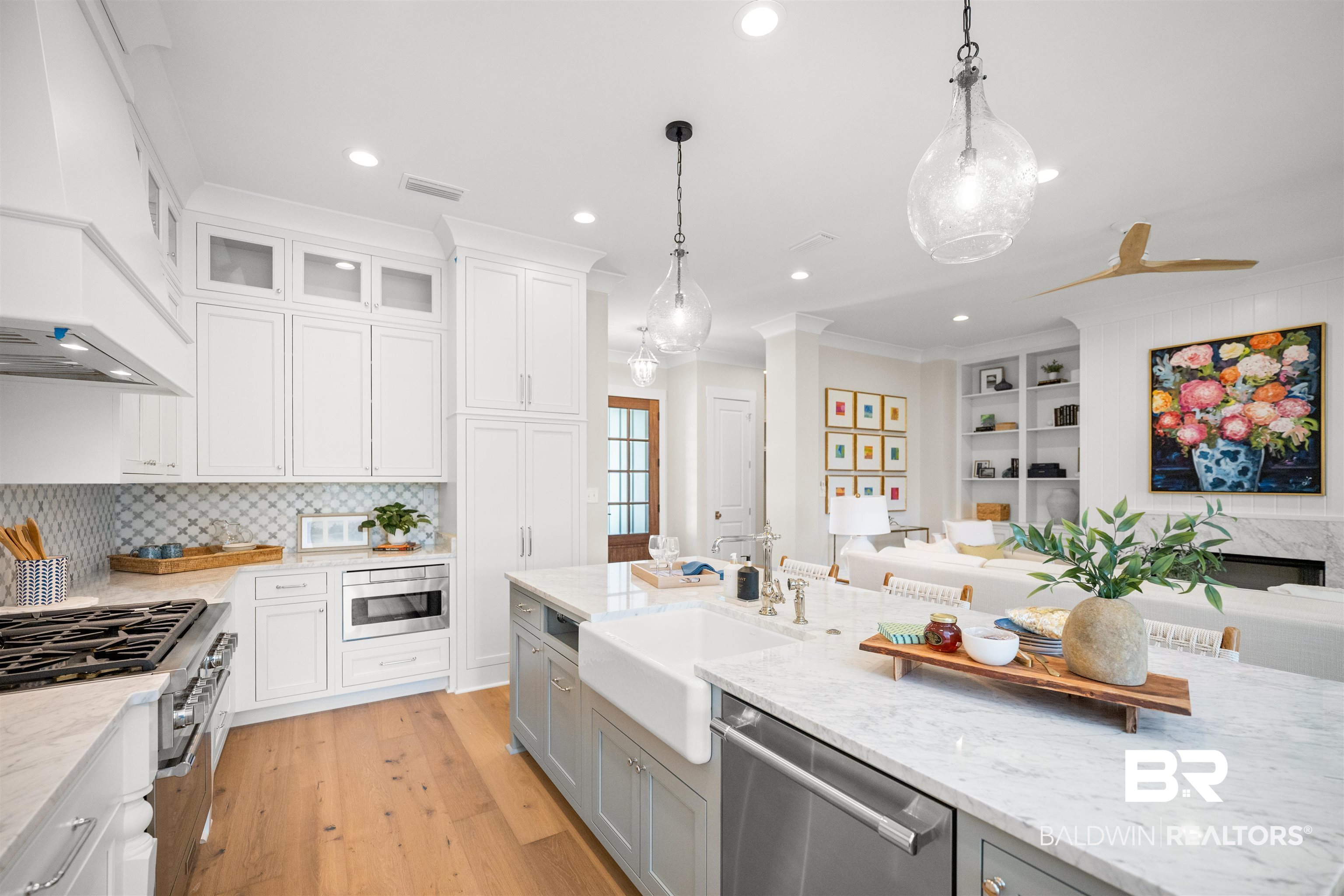 156 Hyacinth Street Fairhope, AL 36532 - Photo 16 of 61 Kitchen featuring hanging light fixtures, light stone countertops, custom range hood, appliances with stainless steel finishes, and white cabinetry