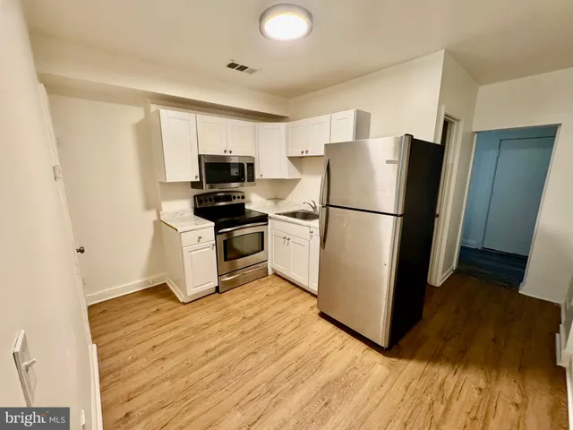 a kitchen with a refrigerator a stove top oven a sink and a hard wood floor