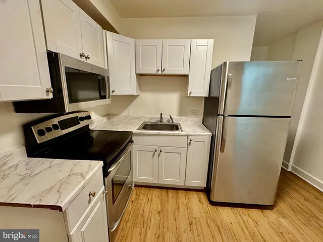 a kitchen with a refrigerator a stove top oven a sink and cabinets