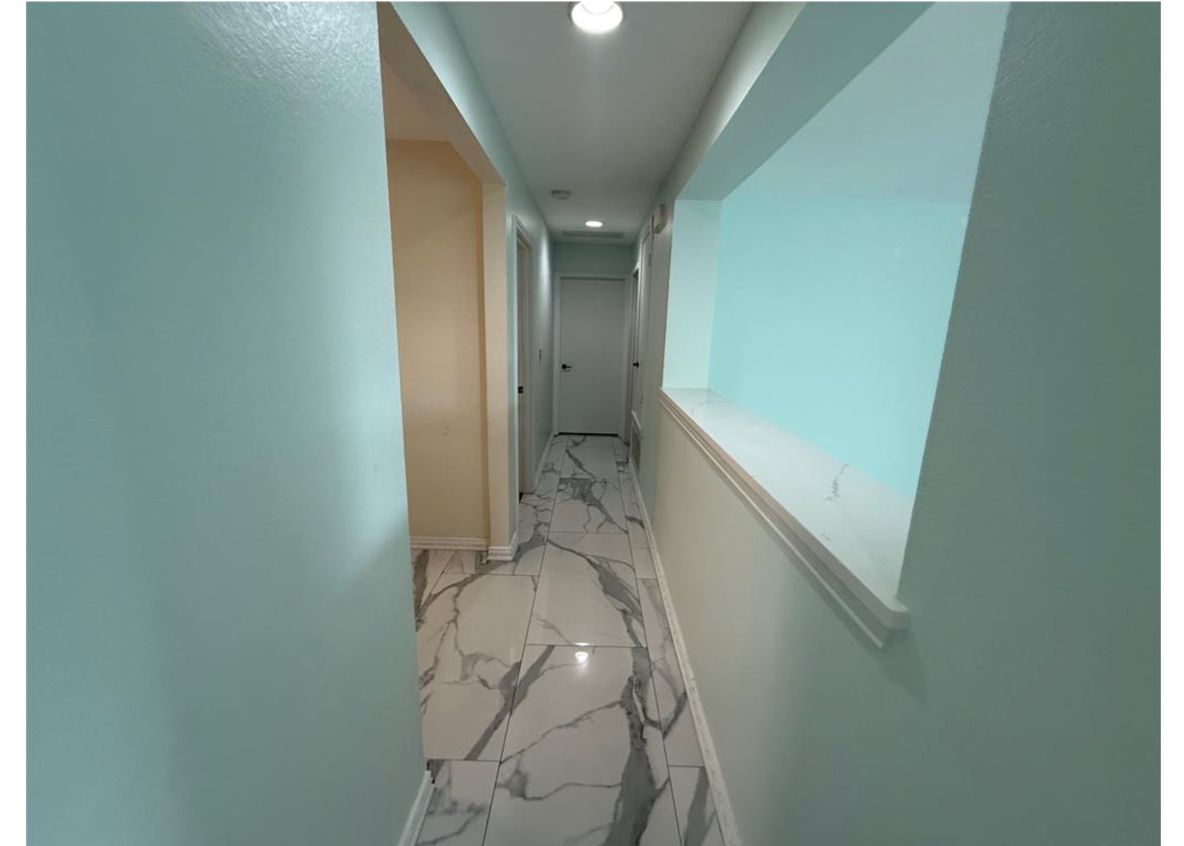 6600 Glebe Path Austin, TX 78754 - Photo 7 of 10 A well-lit hallway features elegant marble-look tile flooring and clean lines leading to a private area.