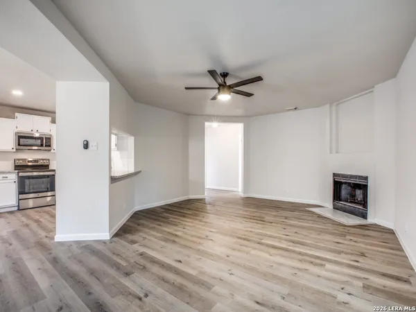a view of an empty room with a window and a kitchen