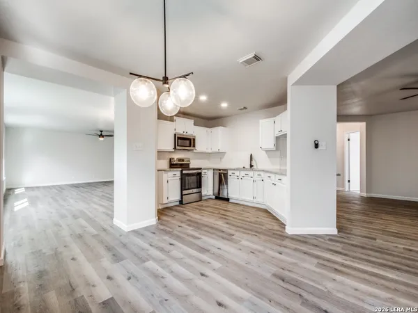 a view of a kitchen with a stove wooden cabinets and wooden floor