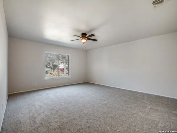an empty room with a ceiling fan and window