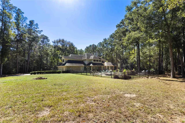 a view of a swimming pool with a yard and large trees