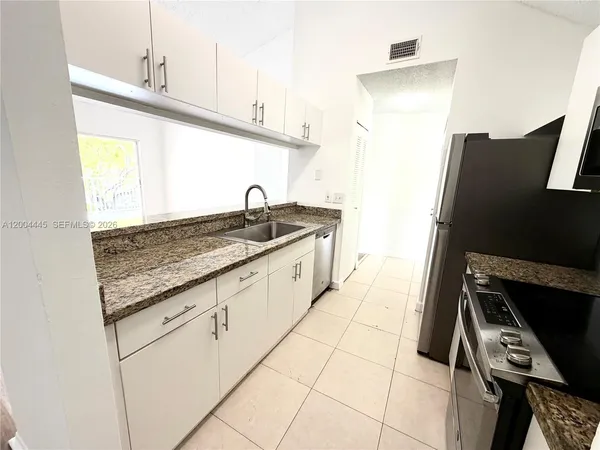 a kitchen with granite countertop a sink a stove and a microwave