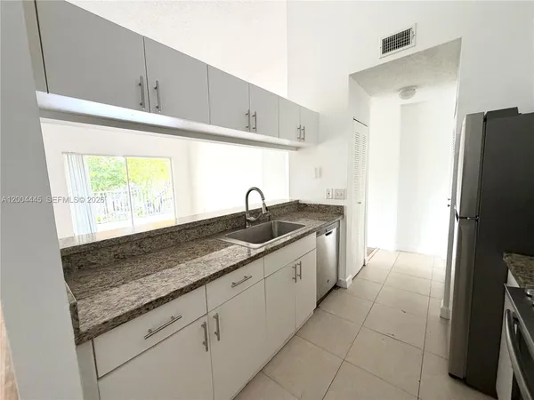 a kitchen with granite countertop a sink a refrigerator and a stove