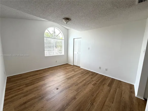 an empty room with wooden floor and windows