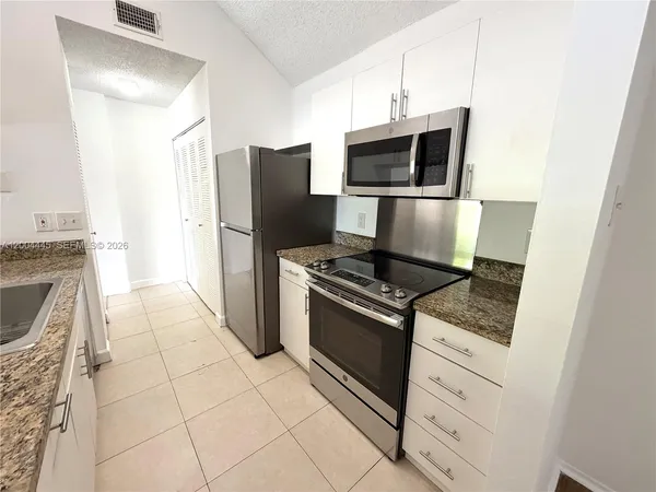 a kitchen with granite countertop a stove and a refrigerator