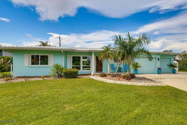 a view of a house with a yard and palm trees