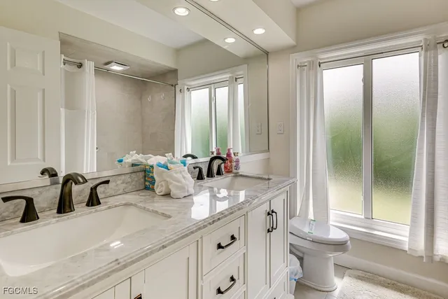 a bathroom with double vanity sinks a toilet and a large mirror